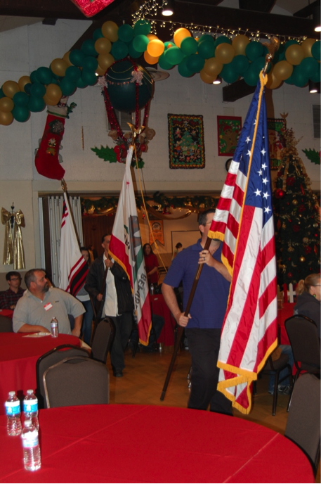 U.S., California and Gabrielino/Tongva flags being led in procession in banquet room decorated for Christmas