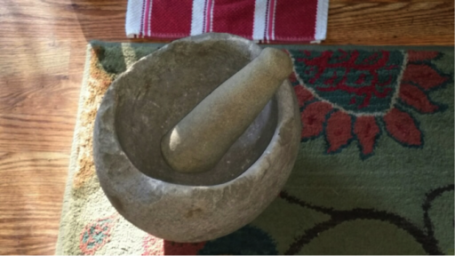 Ancient stone mortar and pestle displayed on colorful modern mat