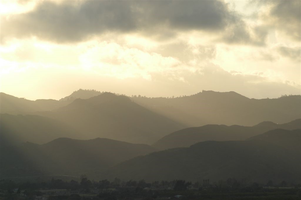 Golden sunlight and clouds above a mountain range in silhouette