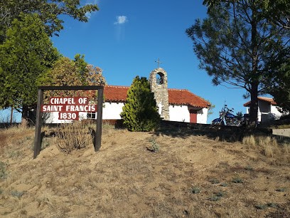 Color photograph of 19th-century adobe chapel with stone belfry and red tile roof
