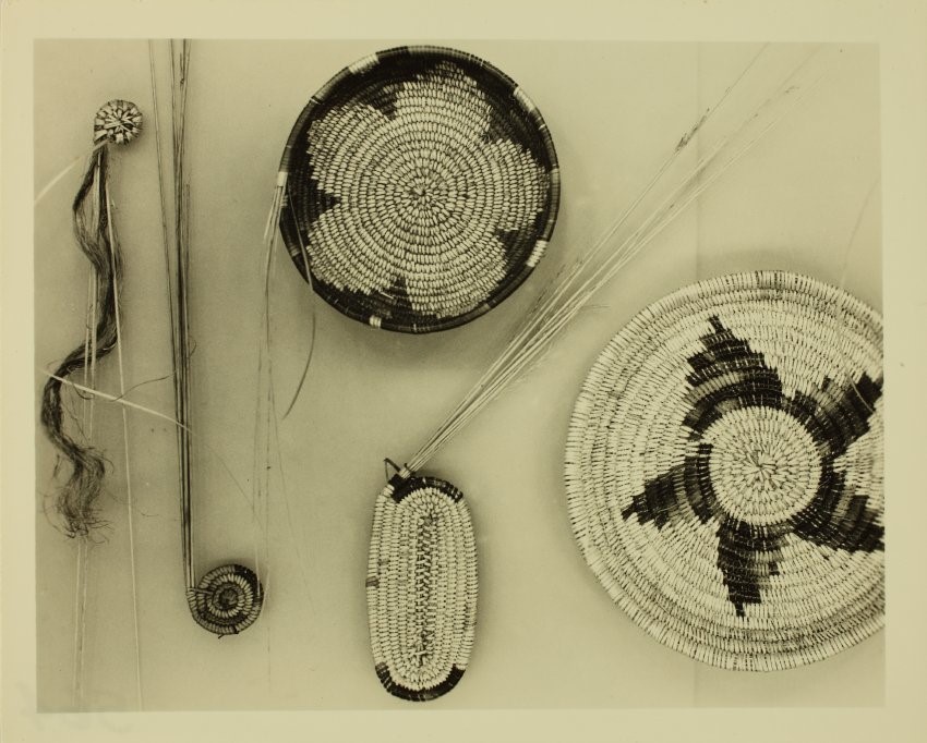 Sepia-toned photograph of coiled basketry at different stages of development from raw materials to finished product
