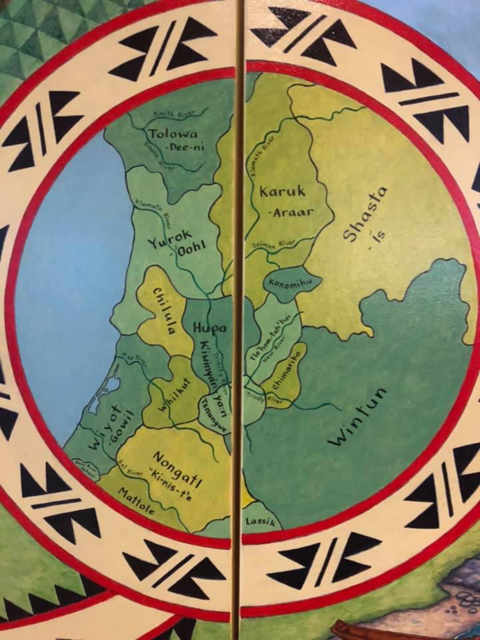 Hand-painted map of parts of Humboldt, Siskiyou, Trinity and Del Norte counties on two panels showing indigenous cultural areas in shades of green, with a traditional pattern in red, beige and black encircling it